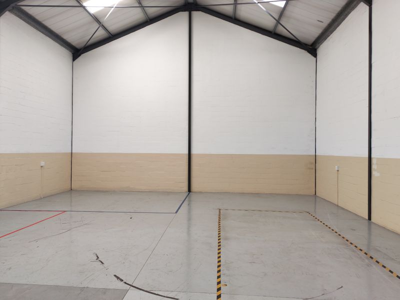 Spacious industrial utility area featuring high ceilings with exposed steel beams, painted block walls, and durable epoxy-coated concrete flooring with marked floor zones.
