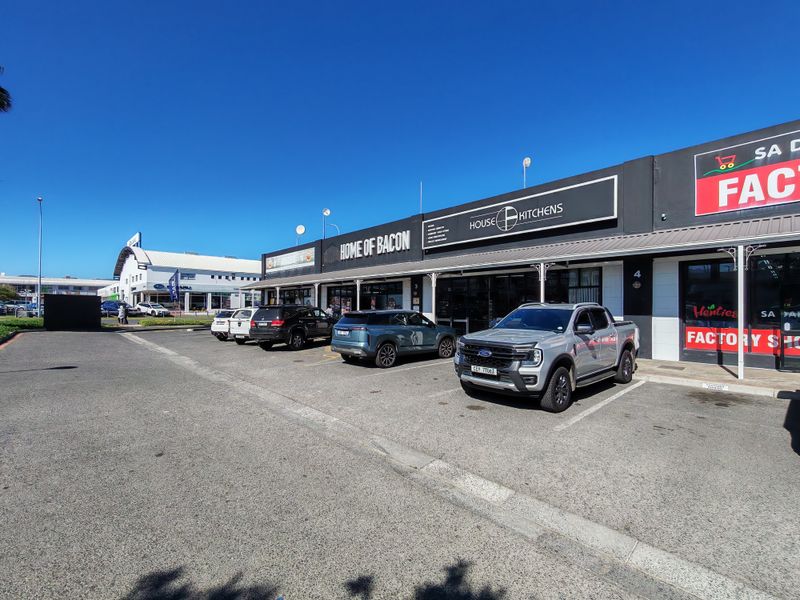 Front exterior view of an industrial commercial complex featuring multiple storefronts, signage, and dedicated asphalt parking bays.