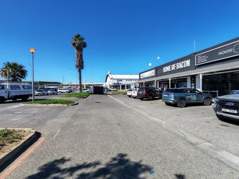 Exterior view of an industrial commercial property featuring a paved parking area and storefront signage.