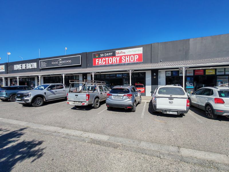 Front exterior view of an industrial retail complex featuring multiple storefronts with prominent signage and dedicated asphalt parking bays.