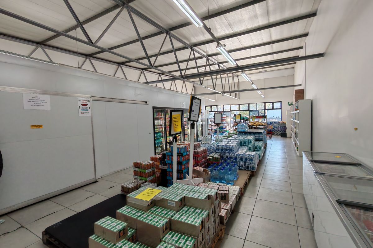 Industrial retail space featuring exposed steel roof trusses, tiled flooring, integrated cold storage units, and commercial refrigeration equipment.