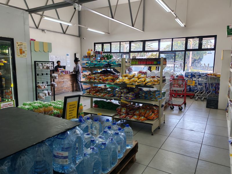 Interior view of an industrial retail space featuring tiled floors, exposed steel roof trusses, and large glass windows providing natural light.