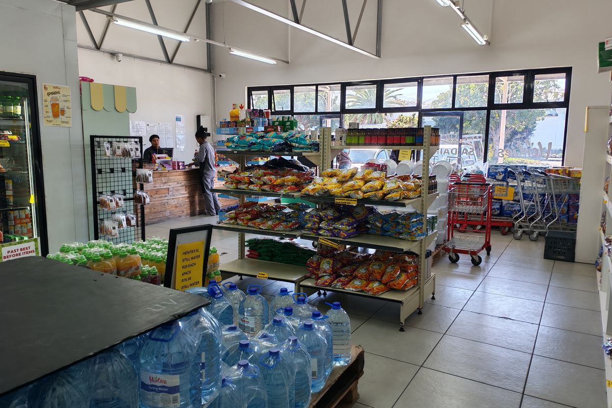 Interior view of an industrial retail space featuring tiled floors, exposed steel roof trusses, and large glass windows providing natural light.
