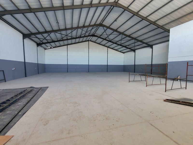 Spacious industrial warehouse unit featuring a high-clearance pitched roof, exposed steel portal frame, and durable concrete flooring, suitable for various commercial or storage uses.