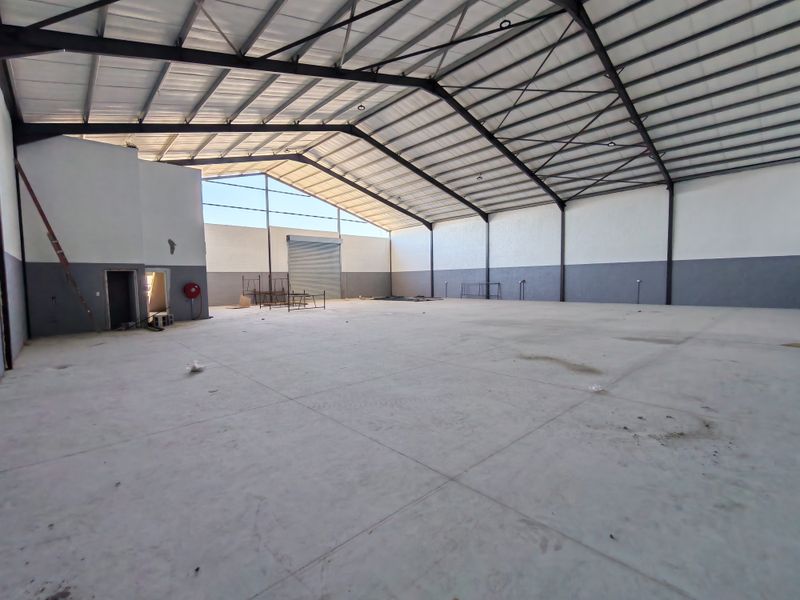 Spacious industrial warehouse featuring a high-clearance steel portal frame, concrete flooring, and a large roller shutter door for efficient access.