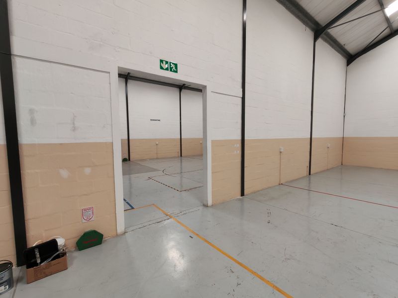 Spacious industrial utility area featuring durable epoxy flooring, painted masonry walls, and a clear open-plan layout suitable for storage or light manufacturing.