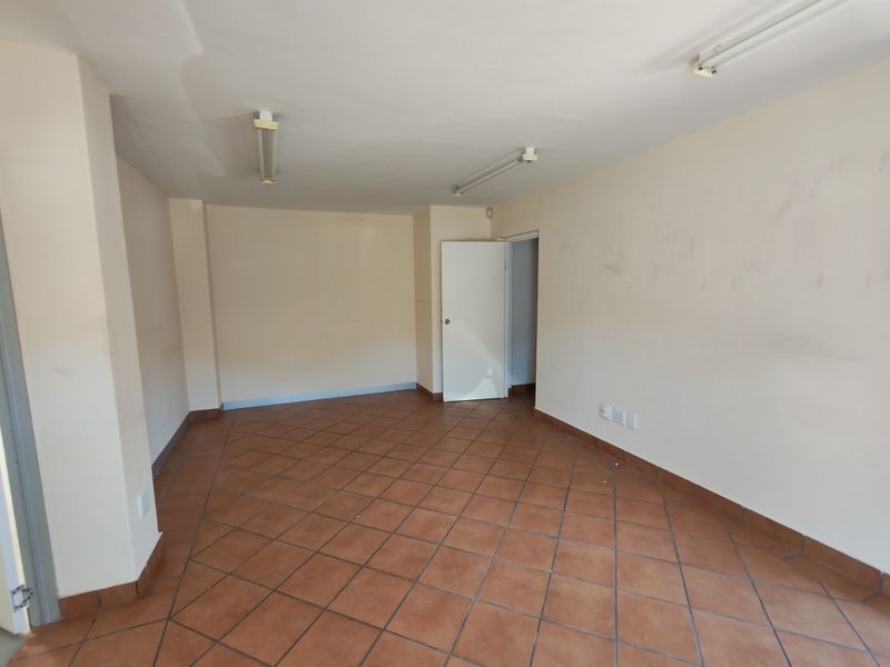 An empty, functional office space featuring terracotta floor tiles, fluorescent lighting, and neutral wall finishes, suitable for various commercial or industrial business applications.