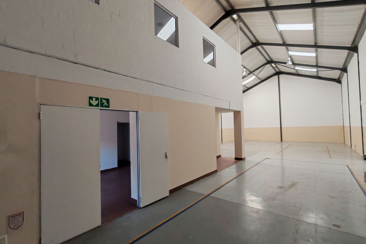 Spacious industrial warehouse unit featuring high ceilings with exposed steel trusses, skylights for natural light, and durable concrete flooring.
