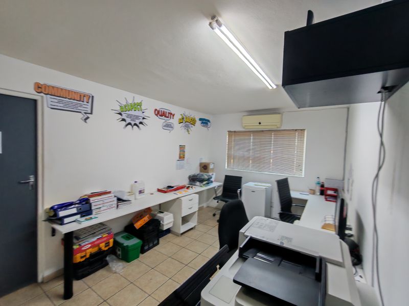 Functional office space featuring tiled flooring, built-in desk workspace, split-unit air conditioning, and venetian blinds for light control.