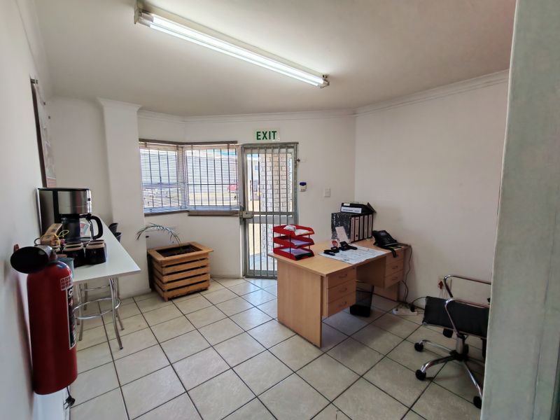 Functional office space featuring tiled flooring, fluorescent lighting, and a secure entrance with a security gate.