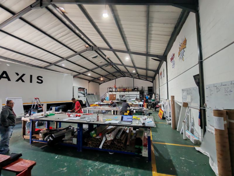 Spacious industrial warehouse facility featuring high ceilings with exposed steel trusses, concrete flooring, and functional open-plan workspace suitable for manufacturing or logistics operations.