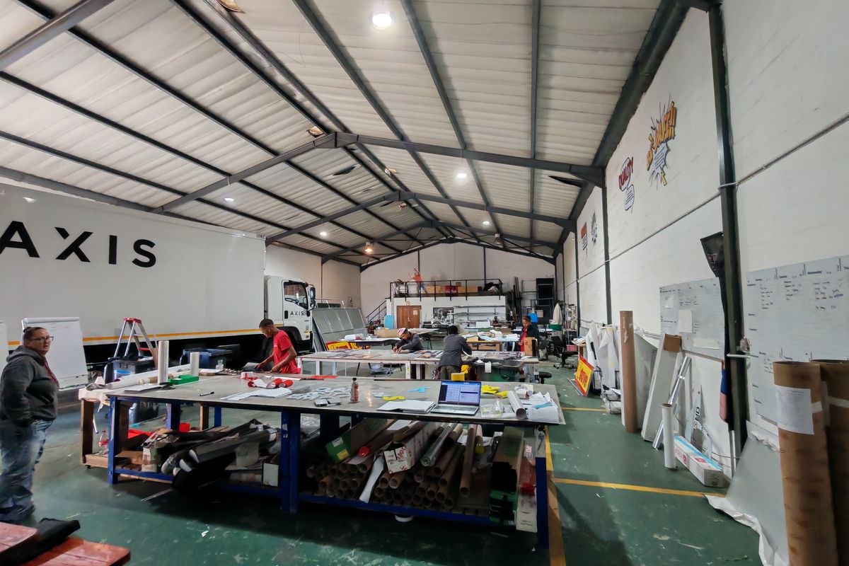 Spacious industrial warehouse facility featuring high ceilings with exposed steel trusses, concrete flooring, and functional open-plan workspace suitable for manufacturing or logistics operations.