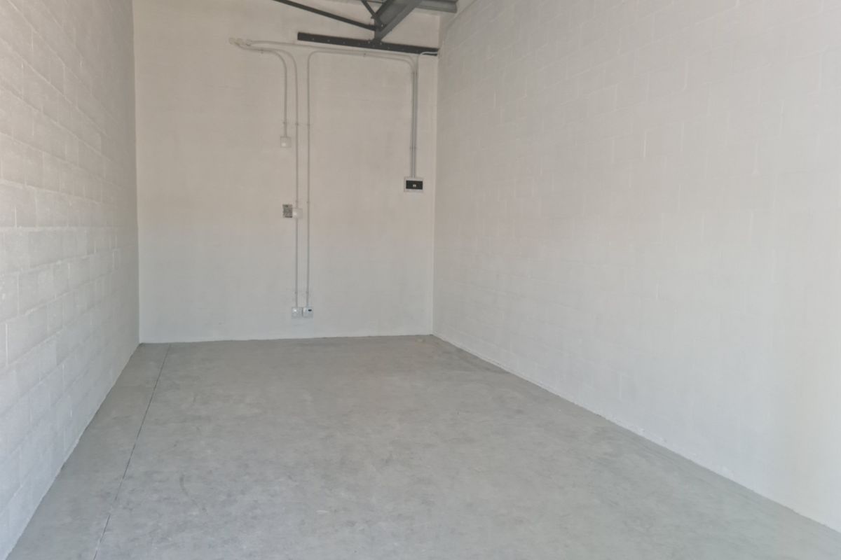 A clean, empty industrial utility space featuring painted concrete block walls, exposed steel roof trusses, and durable concrete flooring.