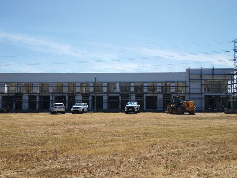 A wide view of an industrial building currently under construction, featuring exposed brickwork, scaffolding, and an unfinished exterior facade.