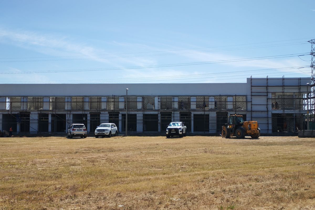 A wide view of an industrial building currently under construction, featuring exposed brickwork, scaffolding, and an unfinished exterior facade.