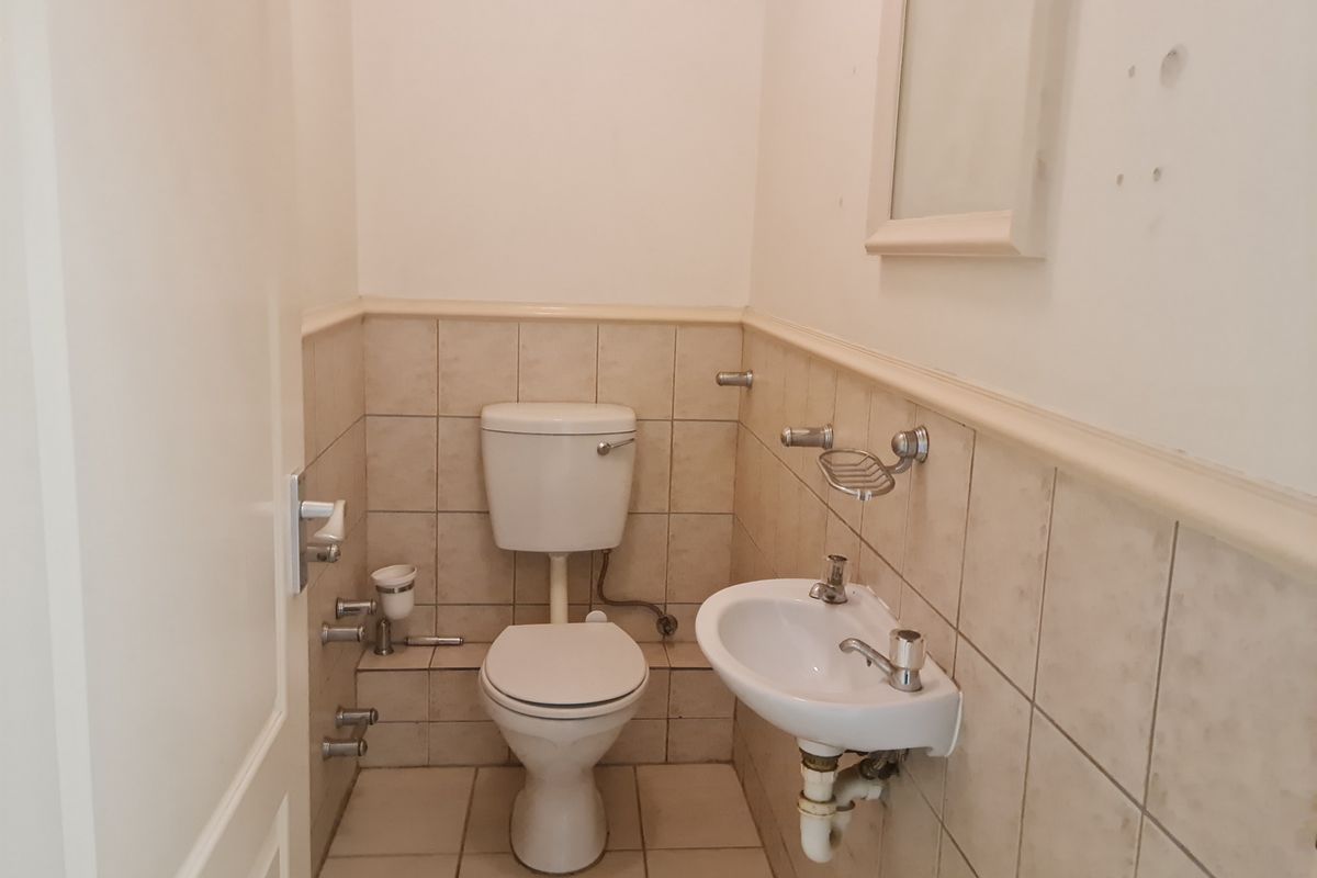 A compact guest bathroom featuring a wall-mounted basin, toilet, and neutral wall tiling with a dado rail.