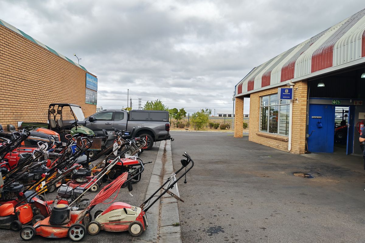 Exterior view of an industrial service facility featuring a paved yard area, brick facade, and metal roof awning.