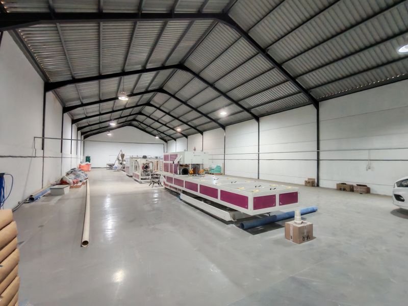 Spacious industrial warehouse featuring high-clearance ceilings with exposed steel trusses, polished concrete flooring, and integrated industrial lighting, suitable for manufacturing or storage operations.