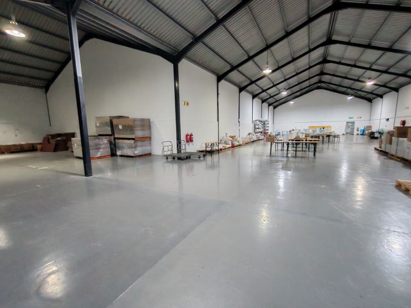 Spacious industrial warehouse featuring a high-clearance steel portal frame, durable epoxy-coated concrete flooring, and functional overhead industrial lighting.