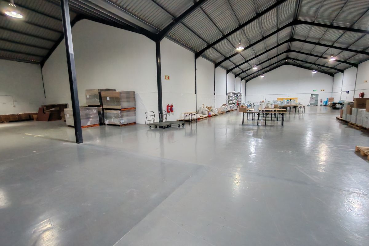 Spacious industrial warehouse featuring a high-clearance steel portal frame, durable epoxy-coated concrete flooring, and functional overhead industrial lighting.