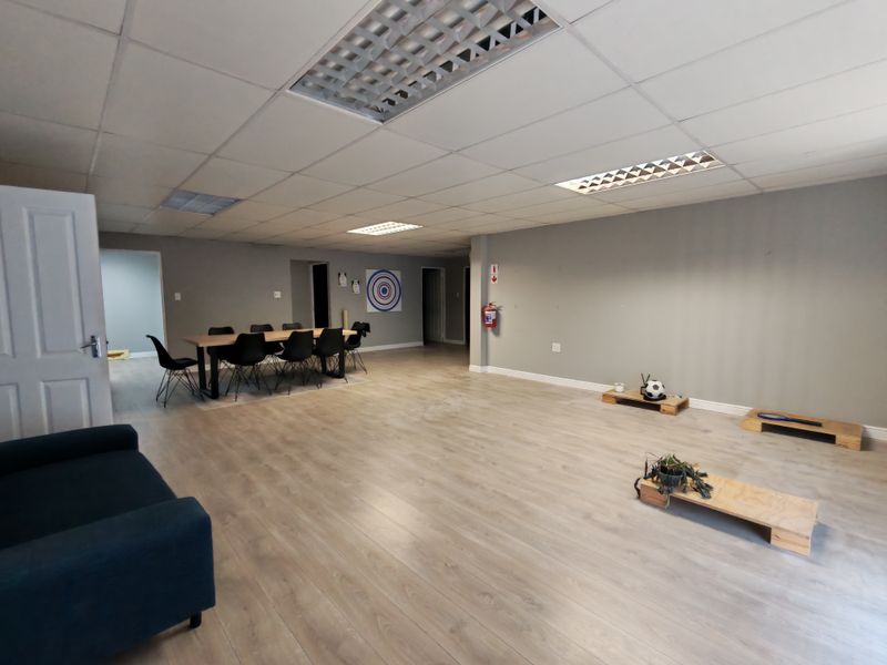 Spacious open-plan industrial office or utility area featuring laminate flooring, suspended ceilings with recessed lighting, and neutral wall finishes.