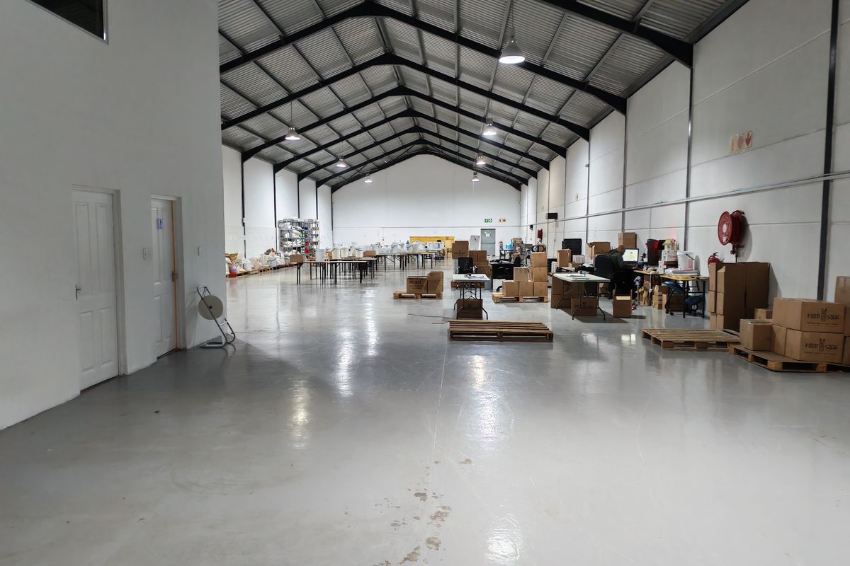 Spacious industrial warehouse unit featuring high ceilings with exposed steel trusses, polished epoxy flooring, and integrated fire safety equipment.