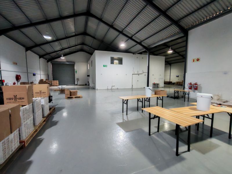 Spacious industrial warehouse unit featuring high ceilings, durable epoxy flooring, a large roller shutter door, and essential fire safety equipment.