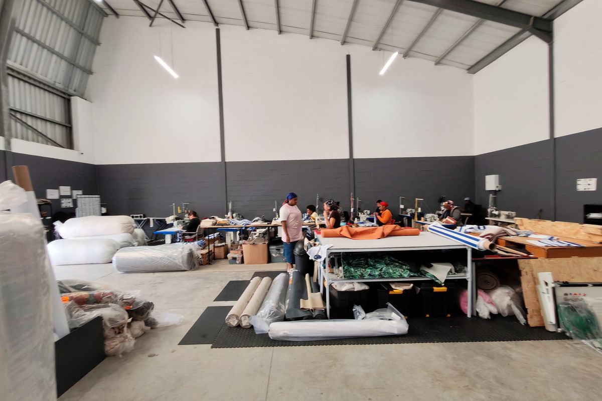 Spacious industrial warehouse unit featuring high ceilings with exposed steel trusses, concrete flooring, and functional high-bay lighting, suitable for manufacturing or storage operations.