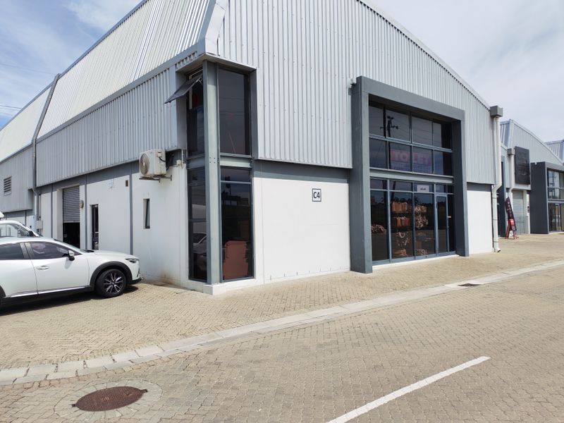 Modern industrial unit featuring corrugated metal cladding, large glass storefront, and paved exterior access, suitable for commercial or warehouse use.