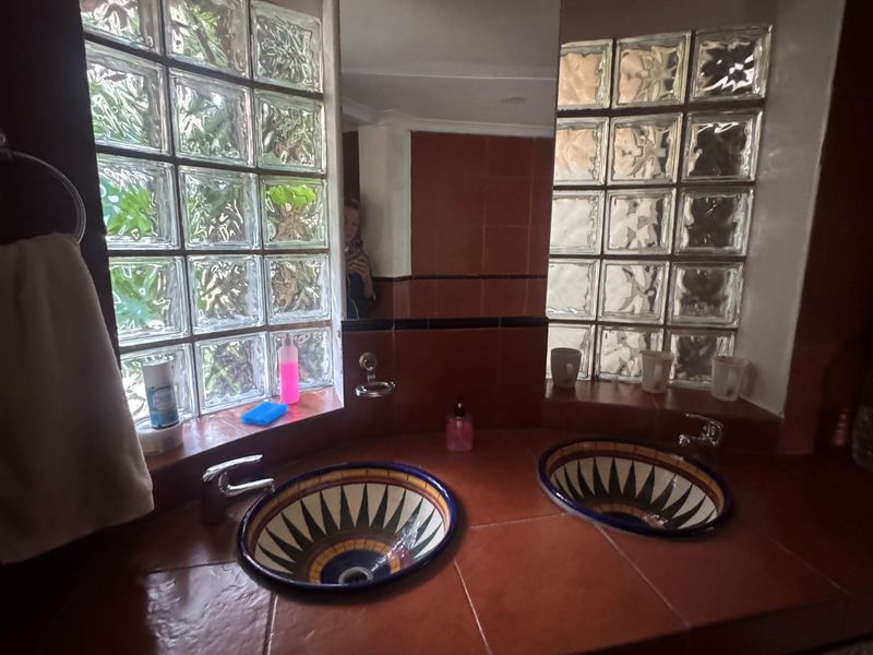 Bathroom featuring a dual vanity with decorative tiled basins, tiled countertop, and distinctive glass block windows providing natural light.