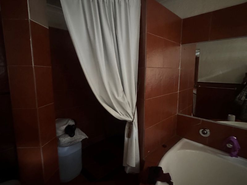 A dated bathroom featuring a built-in bathtub and tiled walls, requiring modernization to improve functionality and aesthetic appeal.