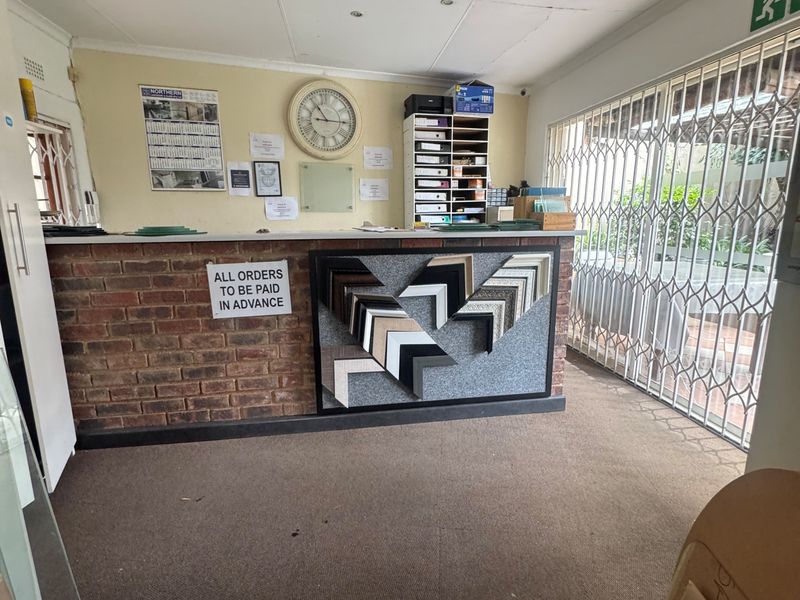 Commercial reception area featuring a brick counter, security gate, and recessed lighting, suitable for a professional office or retail storefront.
