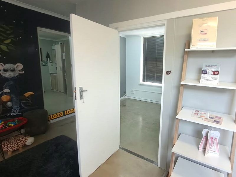 A view through an open doorway into an adjacent room, featuring polished concrete flooring and neutral wall finishes.