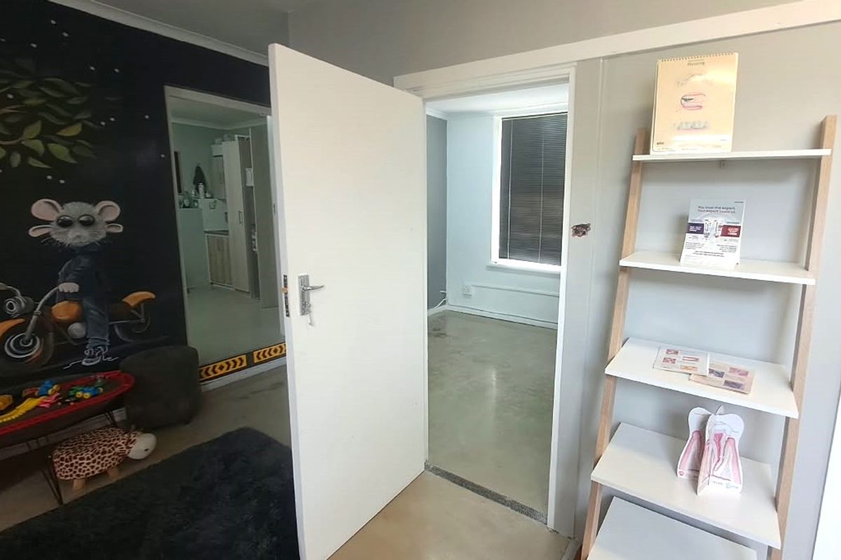 A view through an open doorway into an adjacent room, featuring polished concrete flooring and neutral wall finishes.