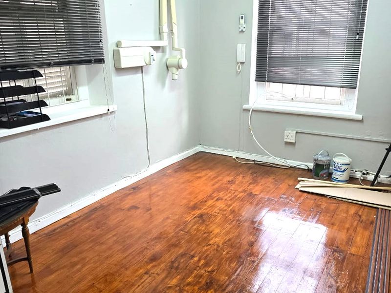 A functional office space featuring polished hardwood flooring, split-system air conditioning, and wall-mounted infrastructure, suitable for professional or medical use.