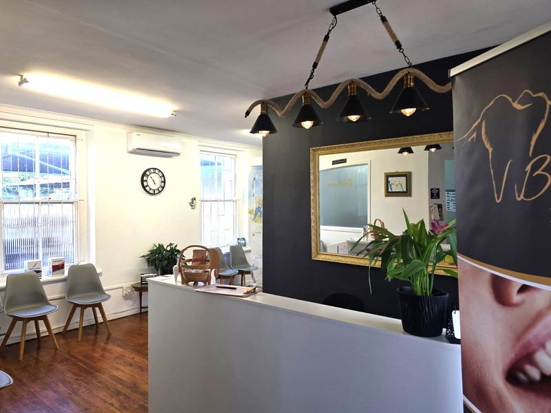 A professional commercial reception area featuring timber flooring, a built-in reception desk, and wall-mounted air conditioning, creating a welcoming entry space.