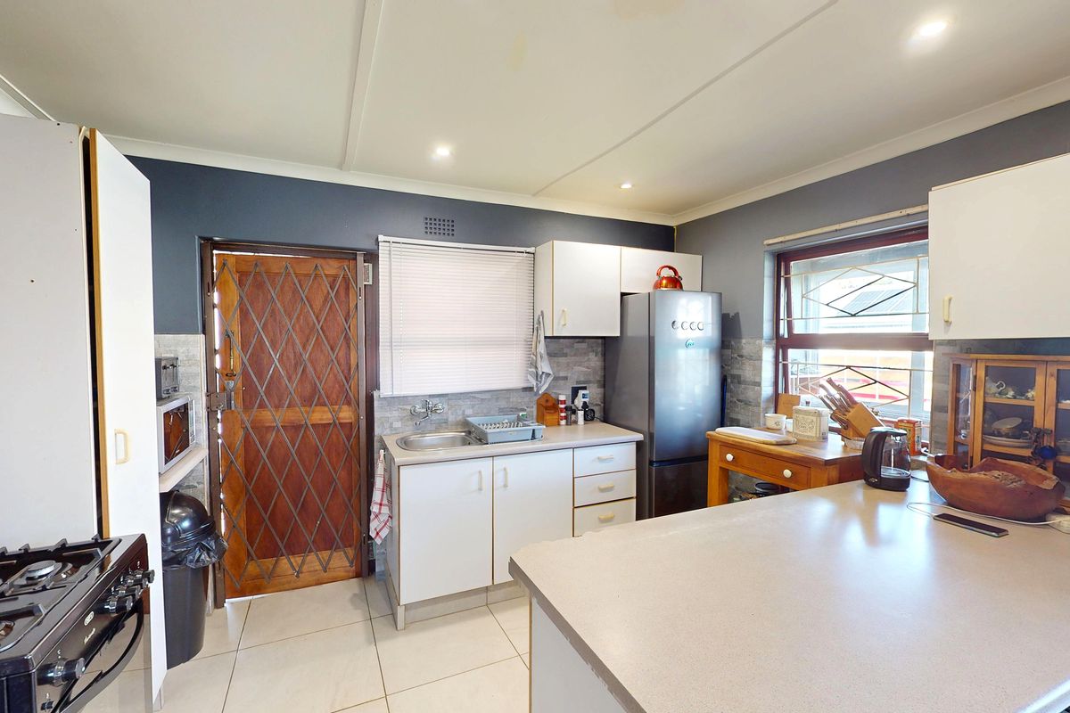 Functional kitchen featuring tiled flooring, built-in cabinetry, stone-look backsplash, and a gas stove, with direct access to an exterior security door.