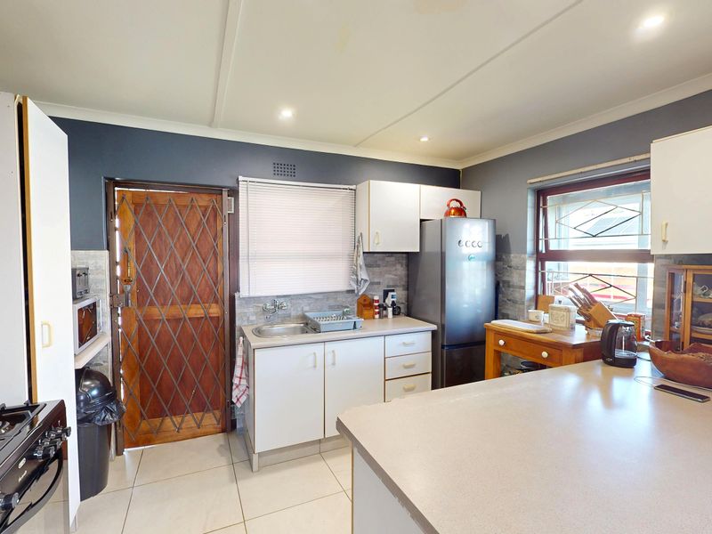 Functional kitchen featuring tiled flooring, built-in cabinetry, stone-look backsplash, and a gas stove, with direct access to an exterior security door.
