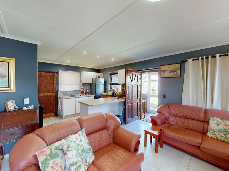 Open-plan living area featuring a functional kitchen with built-in cabinetry and tiled flooring, seamlessly connected to the lounge space.