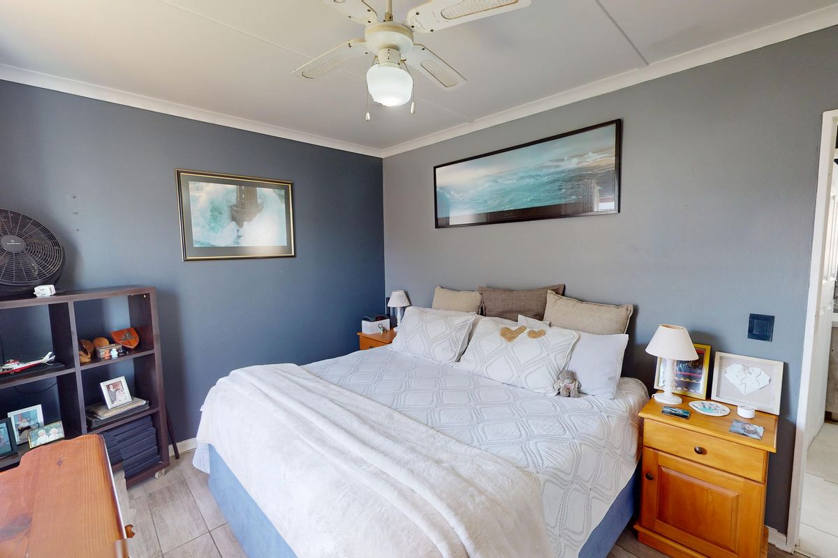 A well-maintained bedroom featuring tiled flooring, a ceiling fan, and direct access to an en-suite bathroom.