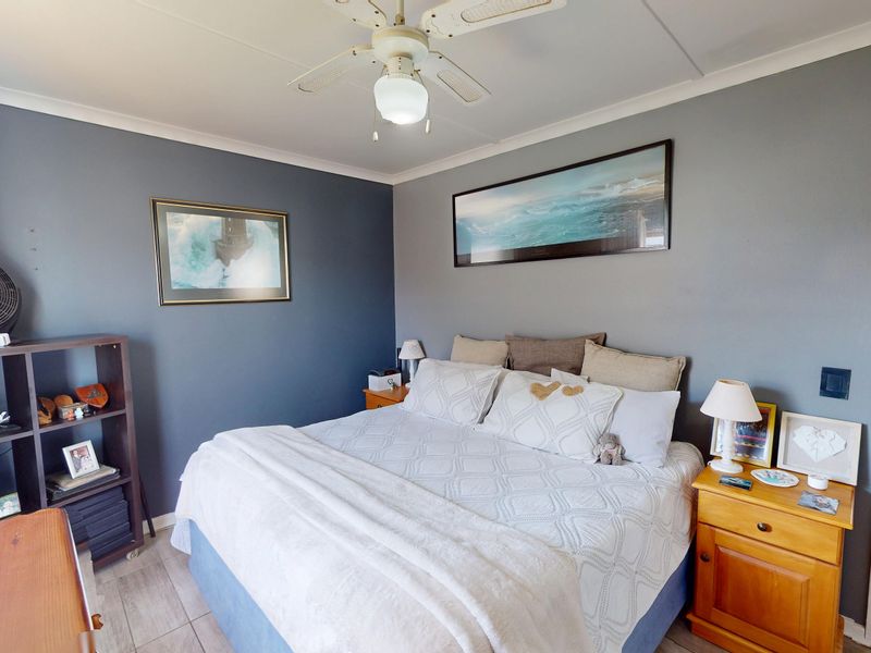 A well-maintained bedroom featuring tiled flooring, a ceiling fan, and direct access to an en-suite bathroom.