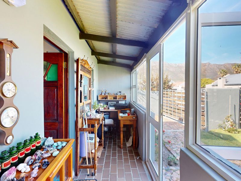 A covered patio area featuring tiled flooring, exposed timber beams, and large glass sliding doors providing access to the garden.
