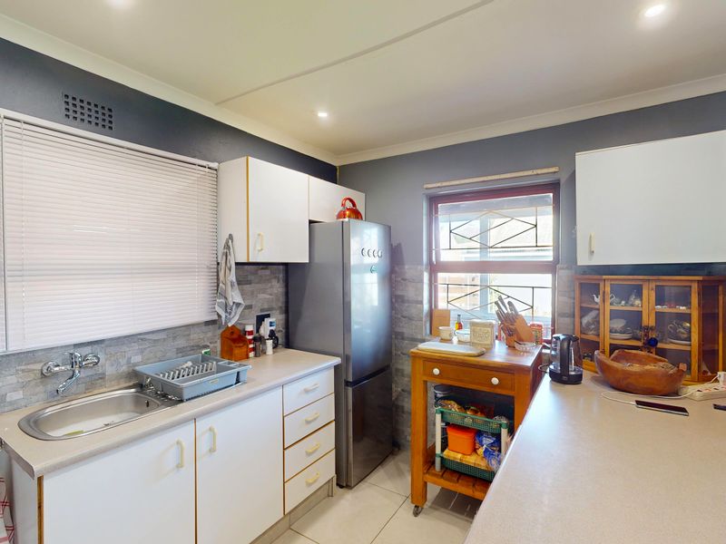 A functional kitchen featuring white cabinetry, laminate countertops, a stainless steel sink, and a tiled backsplash with recessed lighting.