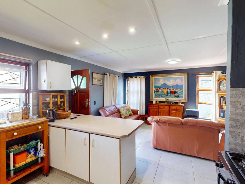 Open-plan living and kitchen area featuring tiled flooring, recessed lighting, and stone-look wall accents, providing a functional and connected living space.