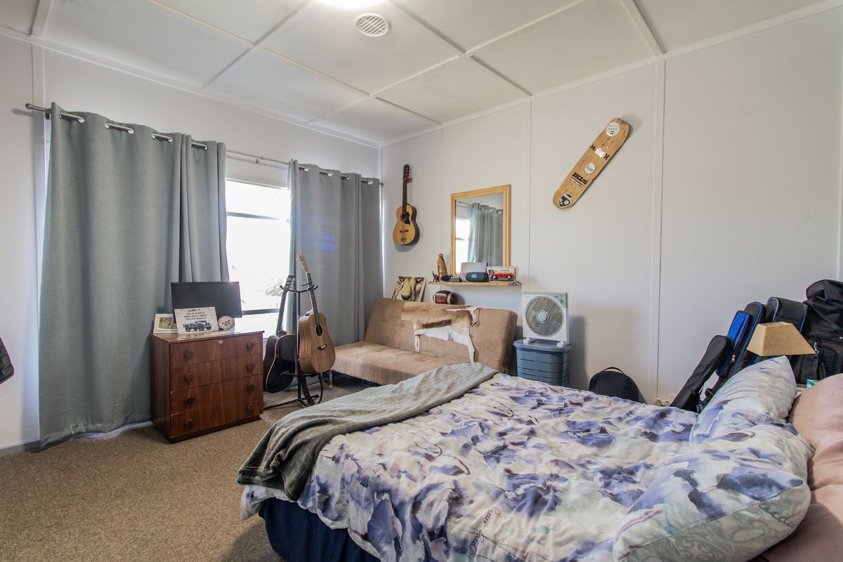 A bedroom featuring a window with curtains, carpeted flooring, and a panelled ceiling.