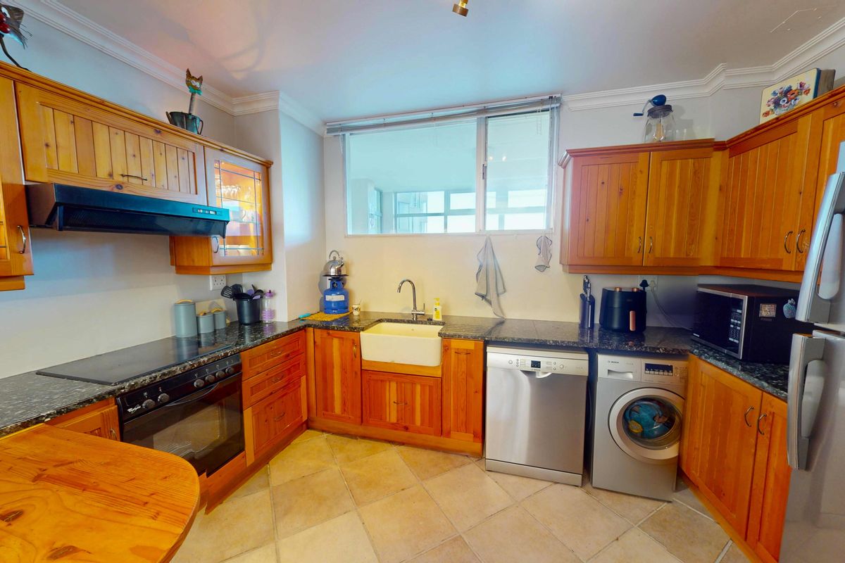 A functional kitchen featuring wooden cabinetry, granite countertops, a farmhouse-style sink, and integrated space for a dishwasher and washing machine.