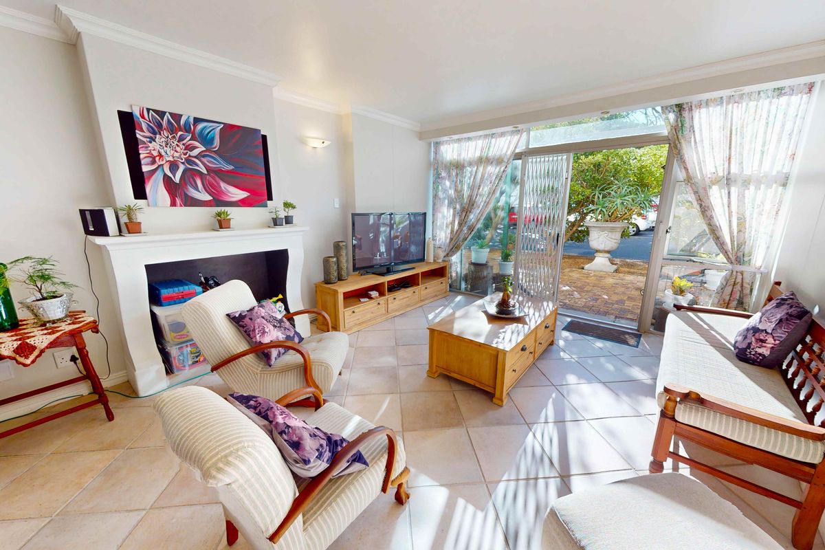 Bright living room featuring a decorative fireplace mantel, tiled flooring, and large sliding glass doors providing direct access to the outdoor patio area.
