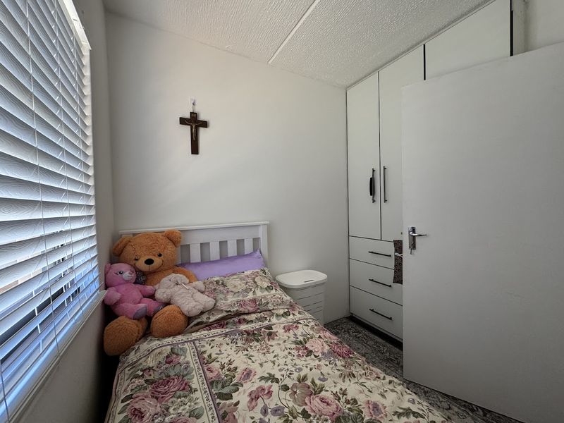 A compact bedroom featuring built-in cupboards and venetian blinds, providing functional storage and natural light control.