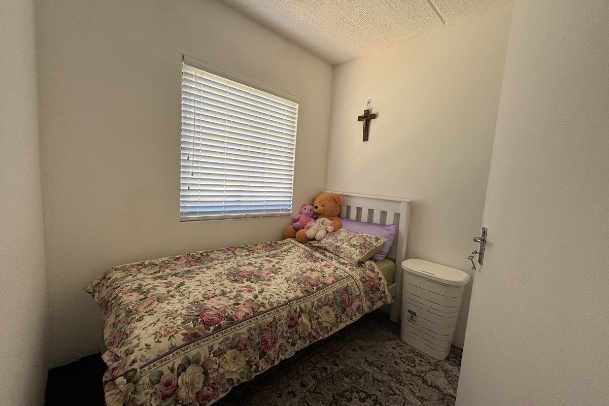 A compact bedroom featuring a window with venetian blinds and a textured ceiling finish.