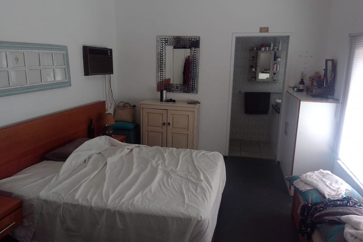A functional bedroom featuring an en-suite bathroom, built-in wall-mounted air conditioning unit, and neutral finishes.